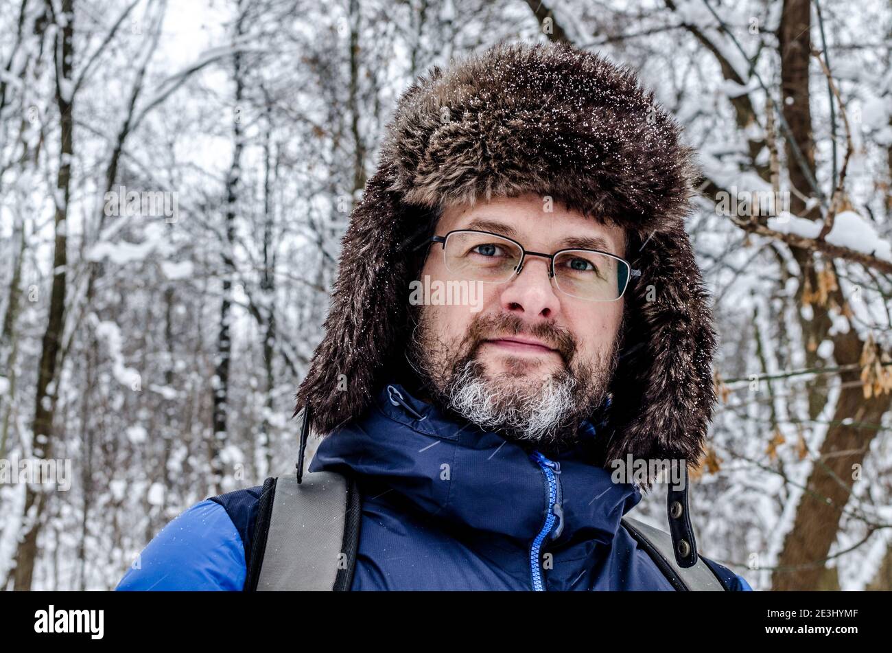 Portrait close up of a mddle aged man with grey beard in a snowy winter forest Stock Photo