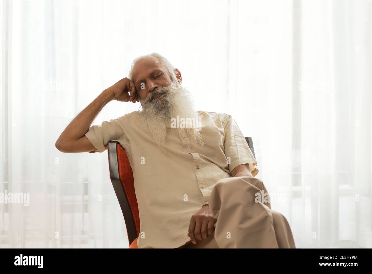AN OLD MAN SITTING AND RESTING ON CHAIR Stock Photo