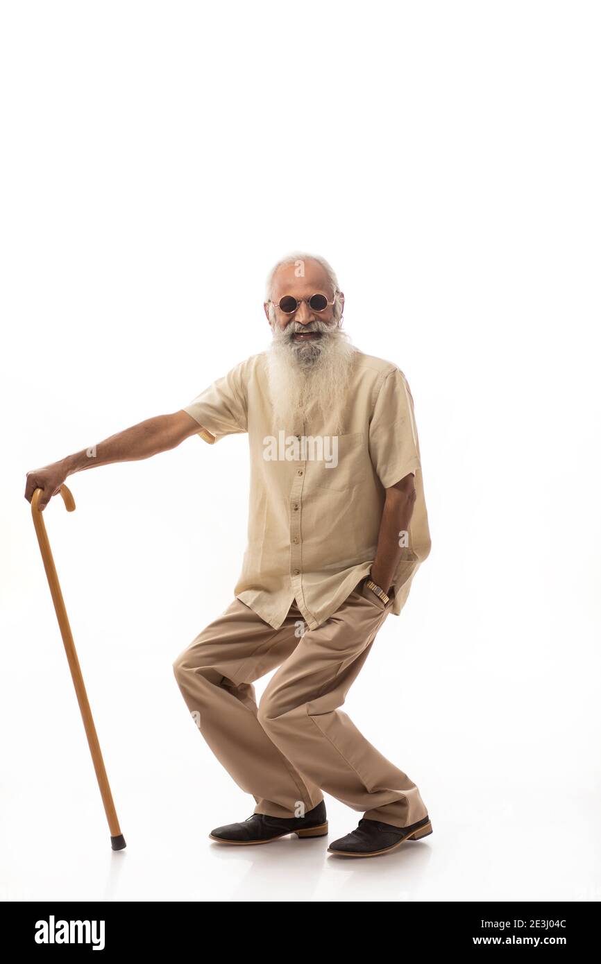 A STYLISH OLD MAN DANCING HAPPILY WITH STICK IN HAND Stock Photo
