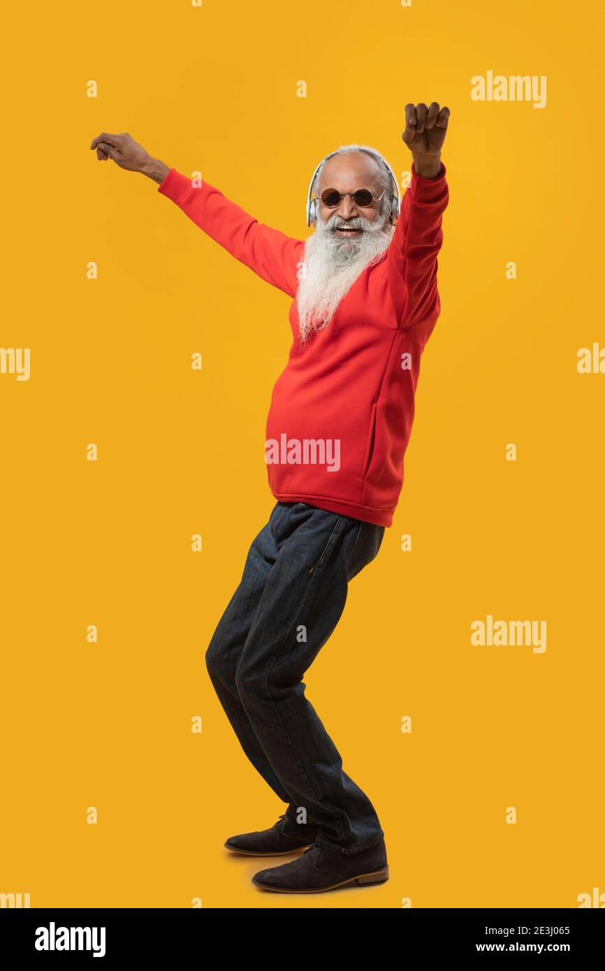 A STYLISH OLD MAN WEARING HEADPHONES AND DANCING TO MUSIC Stock Photo