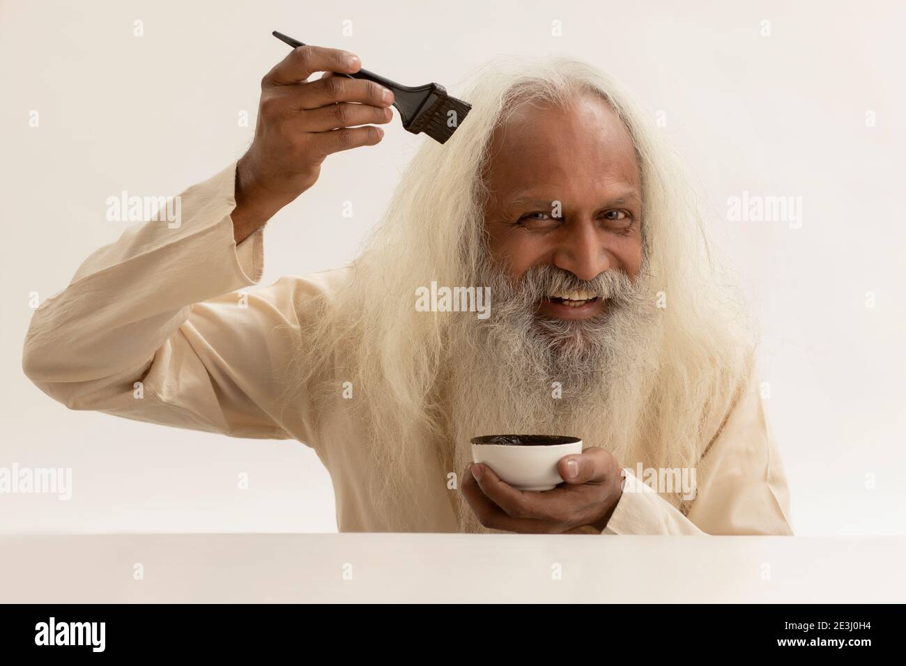 AN OLD MAN USING BRUSH TO COLOUR HAIR Stock Photo