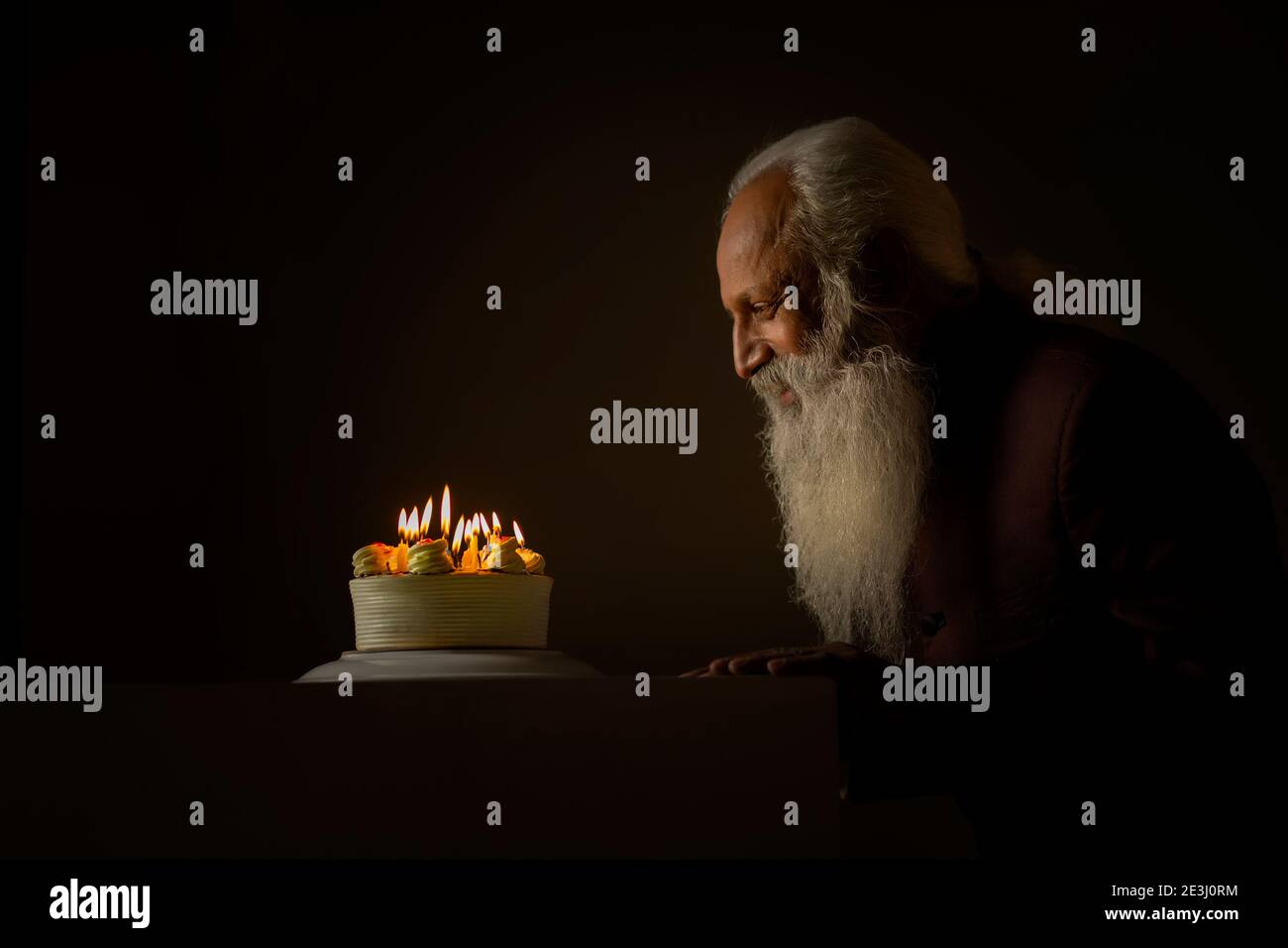 AN OLD MAN HAPPILY SITTING AND LOOKING AT CAKE Stock Photo