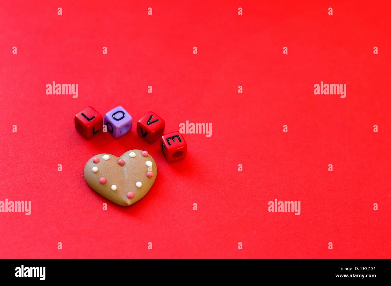 Festive red background. Heart shaped cookies. Colorful wooden cube beads with word 'love'.  Valentine's Day. 14 of February. Ideas of gifts. Flat lay, Stock Photo