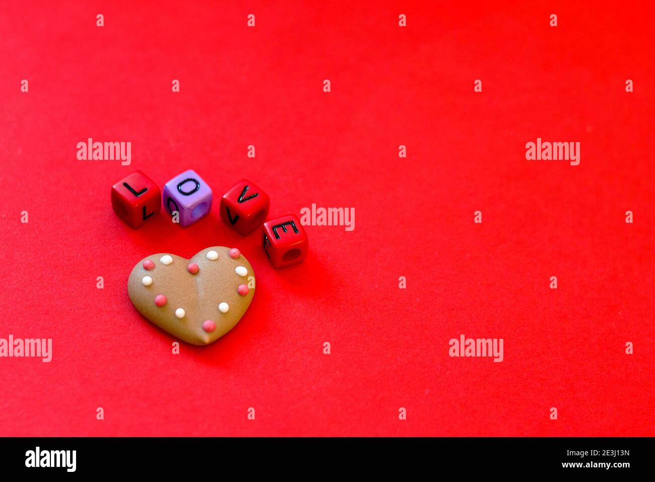 Festive red background. Heart shaped cookies. Colorful wooden cube beads with word 'love'.  Valentine's Day. 14 of February. Ideas of gifts. Flat lay, Stock Photo