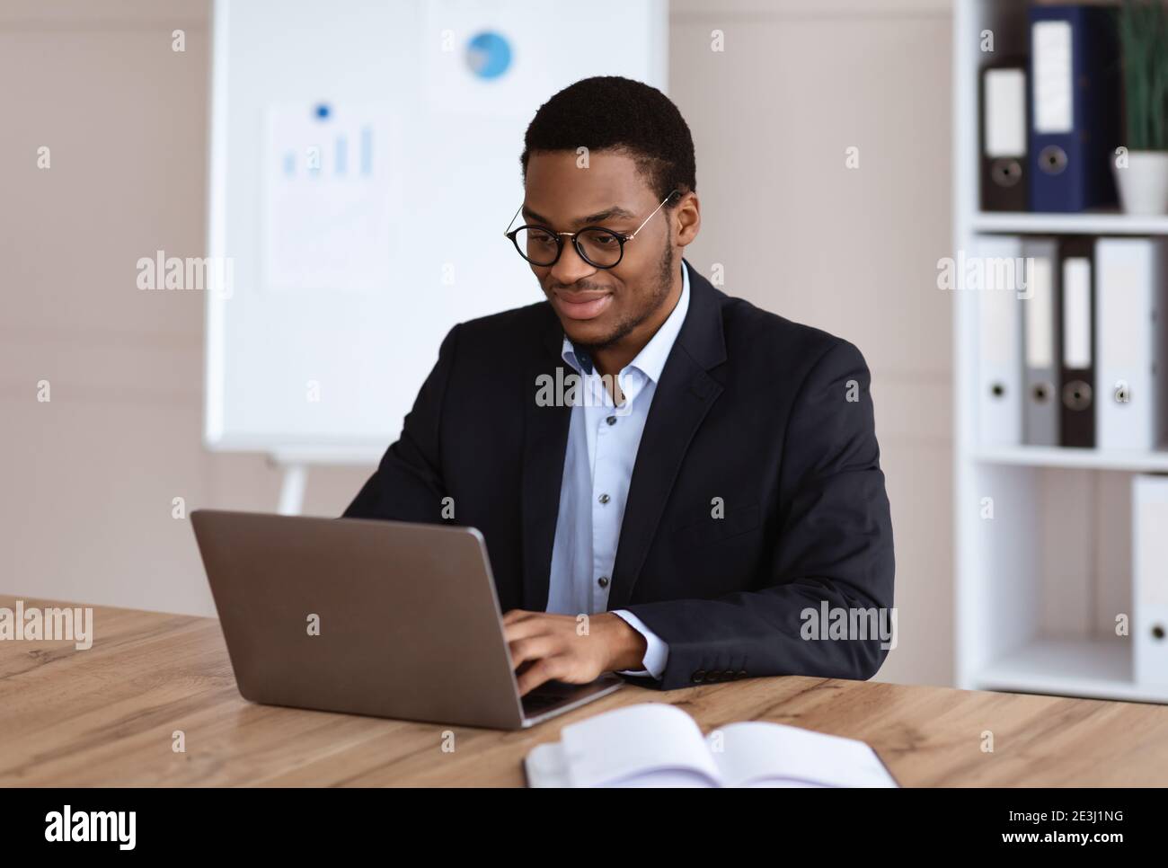 Young black entrepreneur working with laptop, office interior Stock Photo