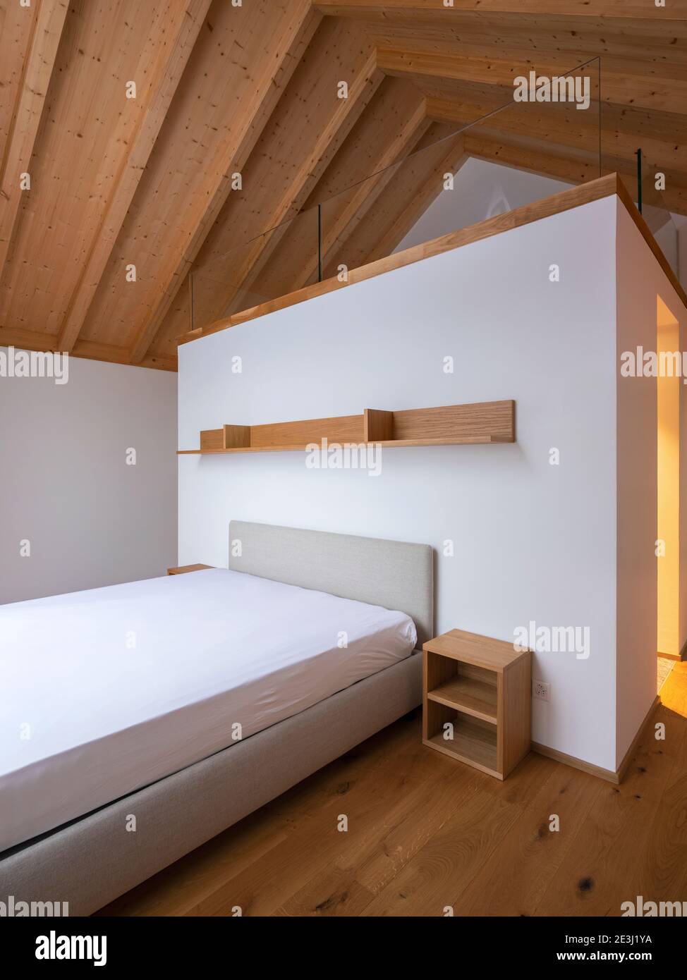 Interior of modern home with white walls and hardwood floors. Bedroom with loft, wodden shelf and bathroom. Nobody inside Stock Photo