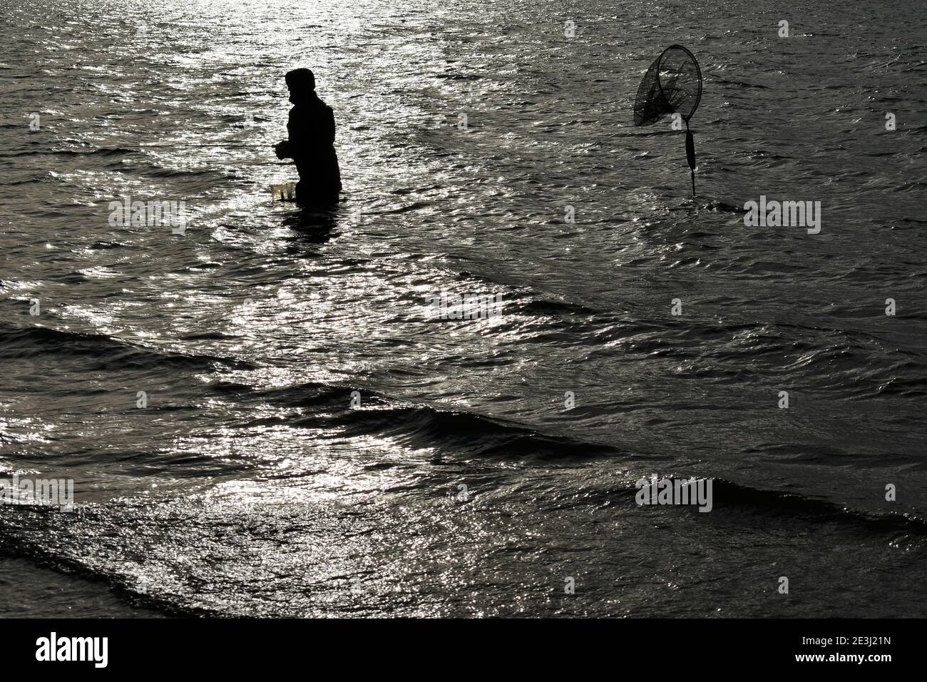 A solo fisherman Fly fishing silhouette at Grafham Water in Bedfordshire in wintertime Stock Photo