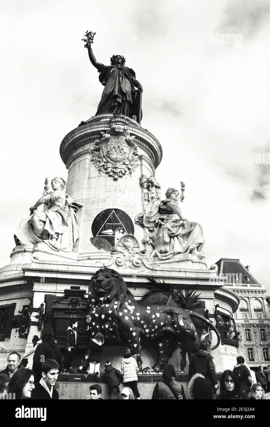 PARIS, FRANCE - JANUARY 28, 2017: Hearts with prayers for peace on lion beneath the Statue of Republique and playing children at Place de la Republiqu Stock Photo