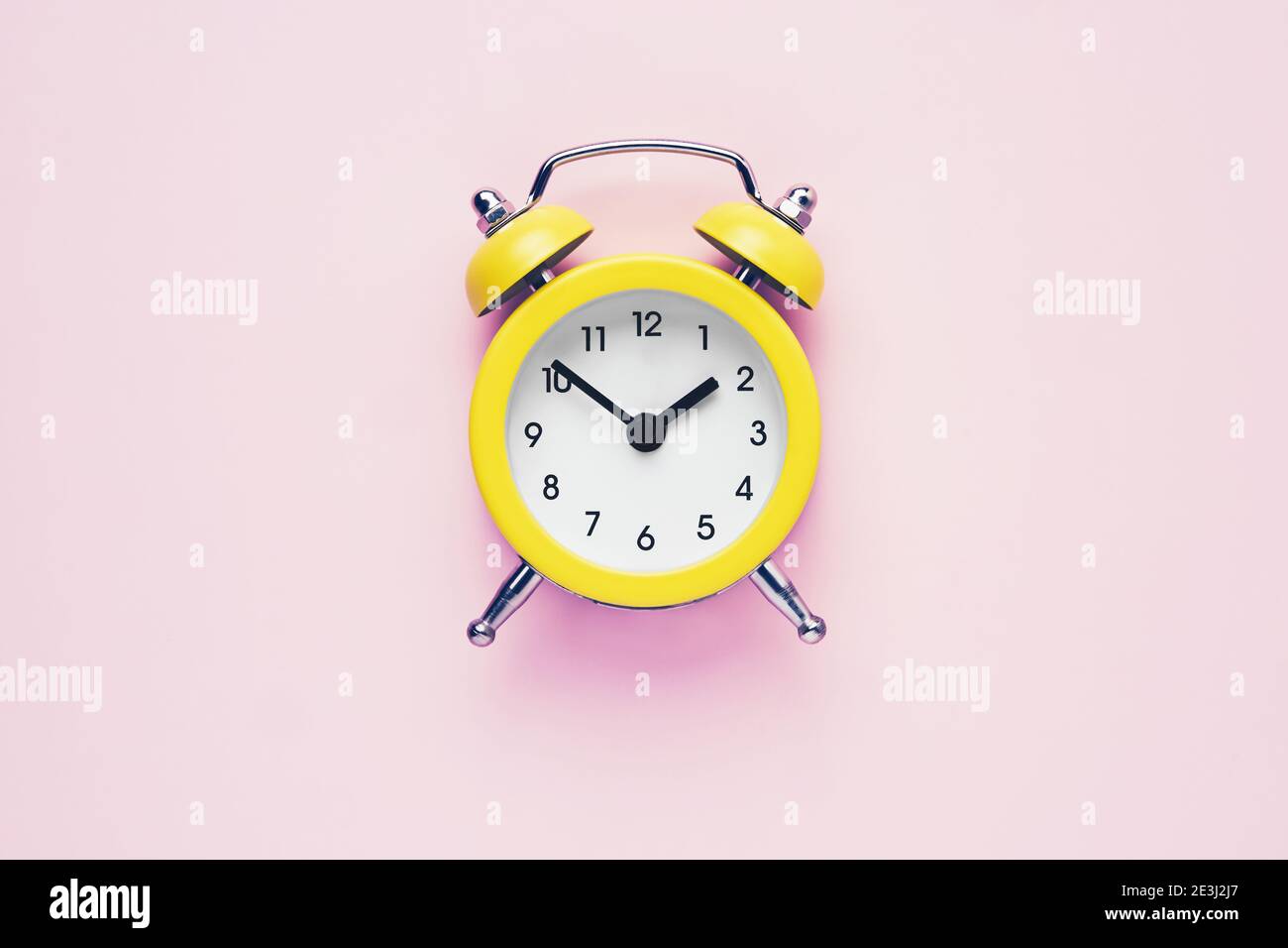 Yellow vintage alarm clock on a pink background. Daylight saving