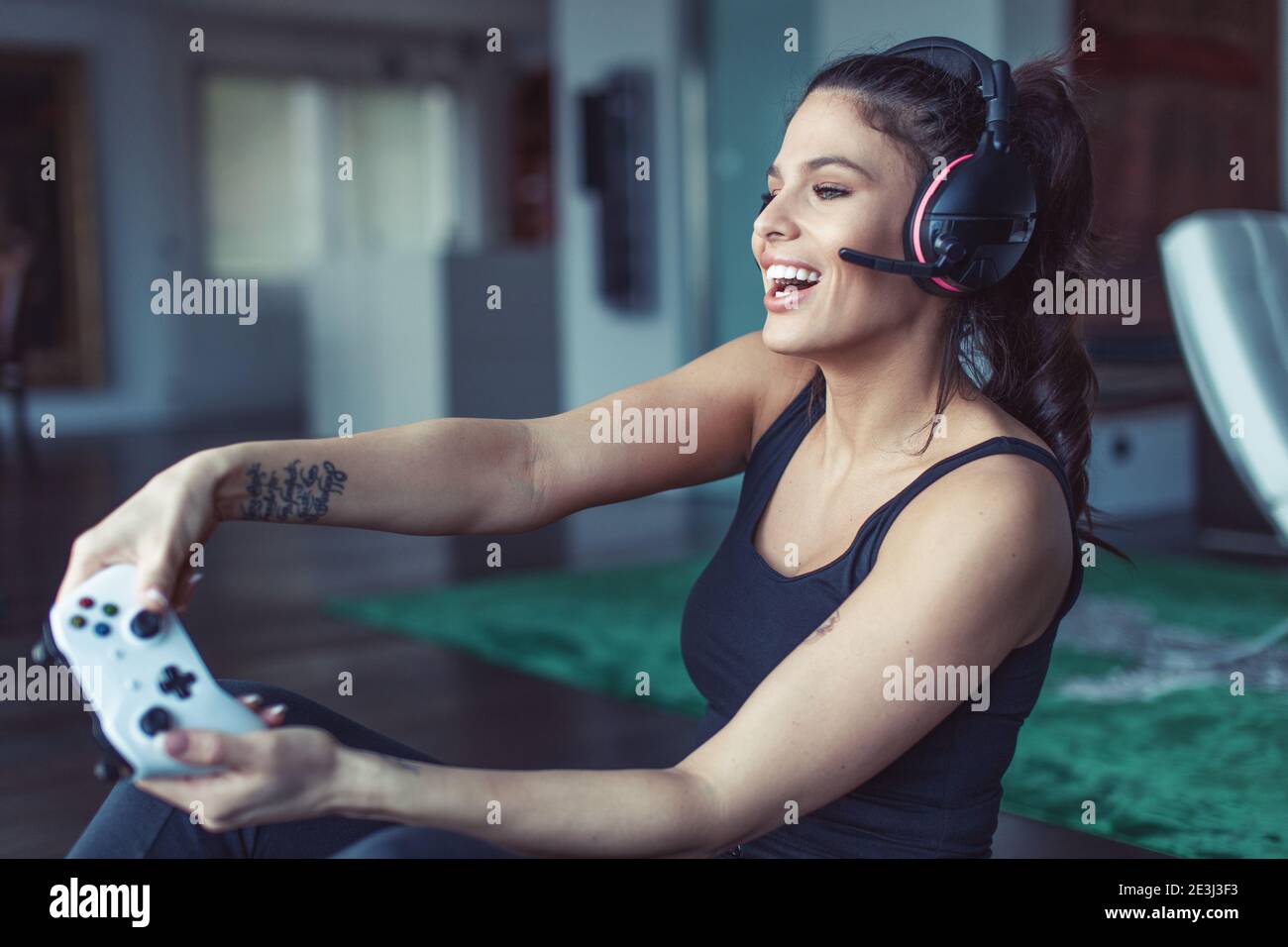 Happy young Caucasian gamer woman playing on console indoors Stock Photo