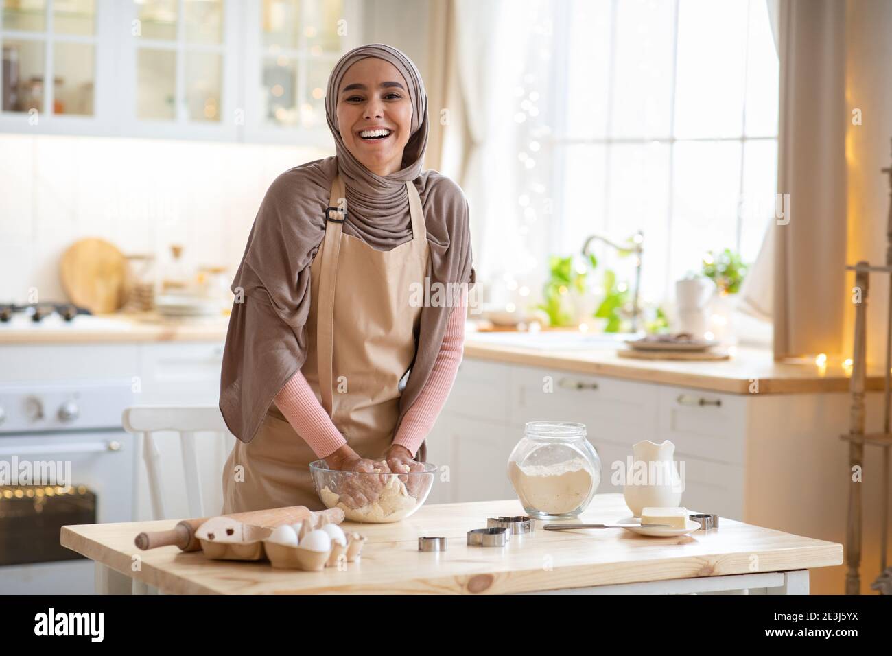 Baking Concept. Joyful Muslim Woman In Hijab Kneading Dough In Kitchen ...