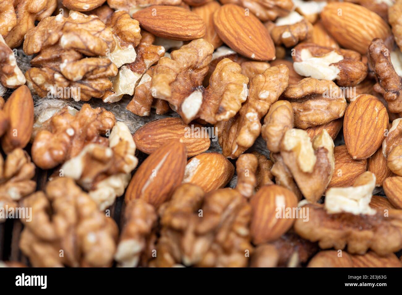 Almonds and walnuts scattered on the table. Close-up, selective focus Stock Photo