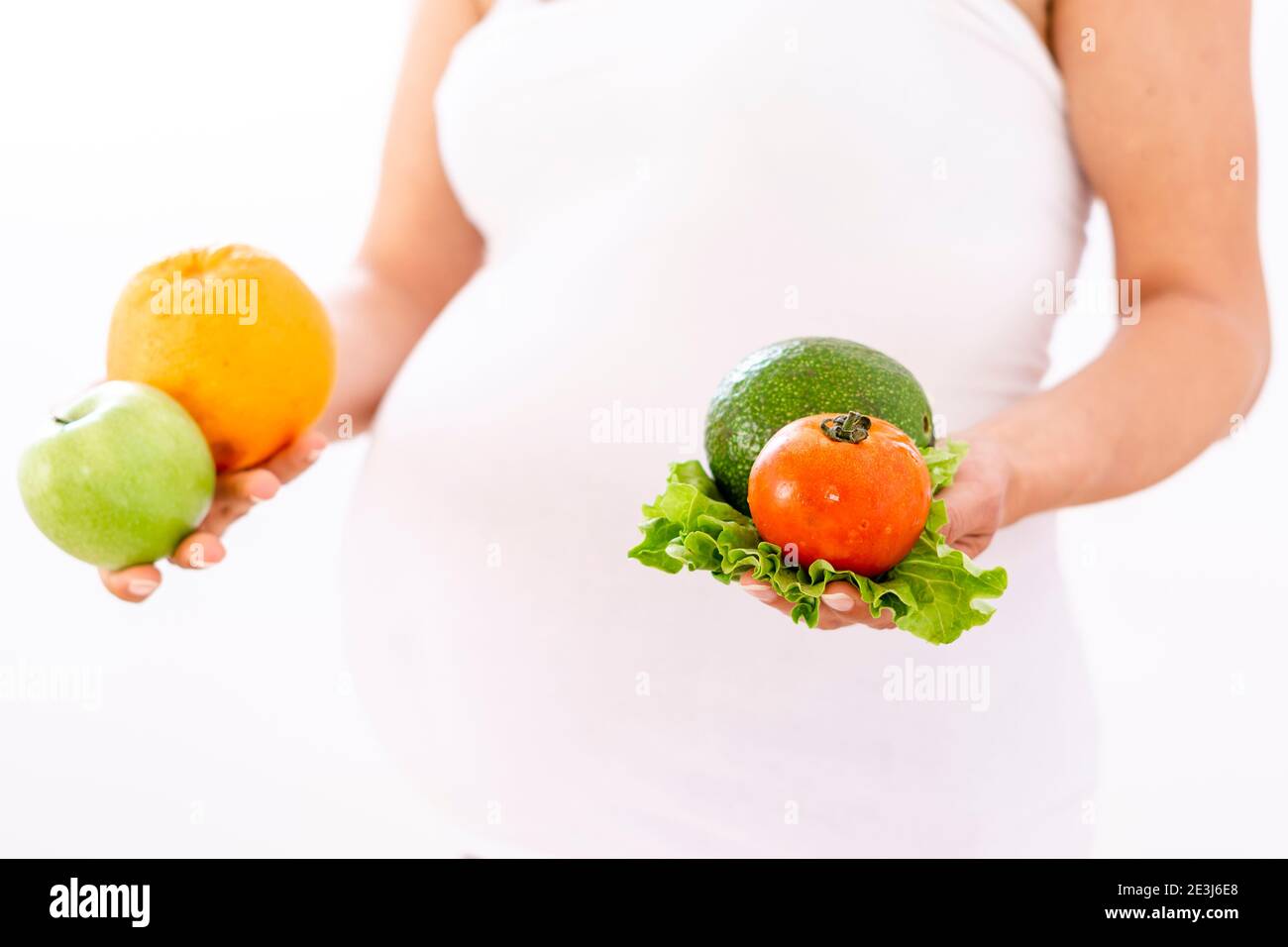 Pregnant woman holding organic vegetables and fruits in her hands Stock