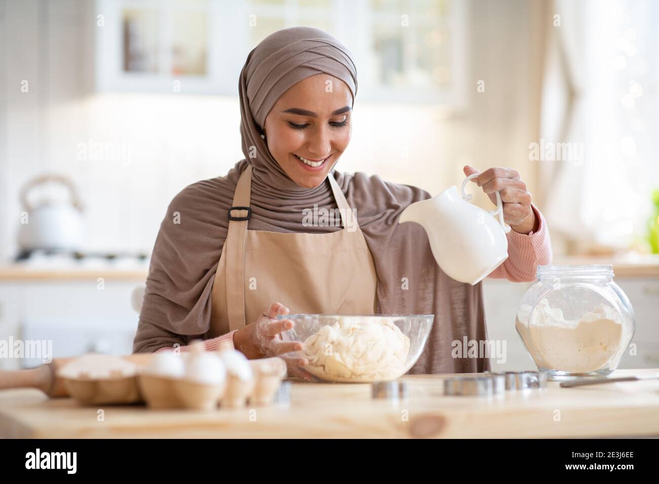 Home Bakery. Beautiful islamic lady in hijab preparing dough for pie Stock Photo