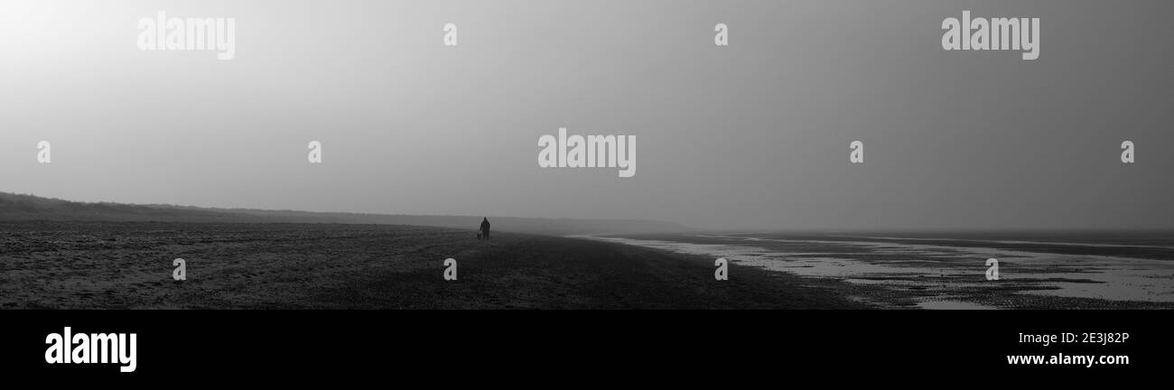 A lonely figure on a misty beach in Winter. Stock Photo