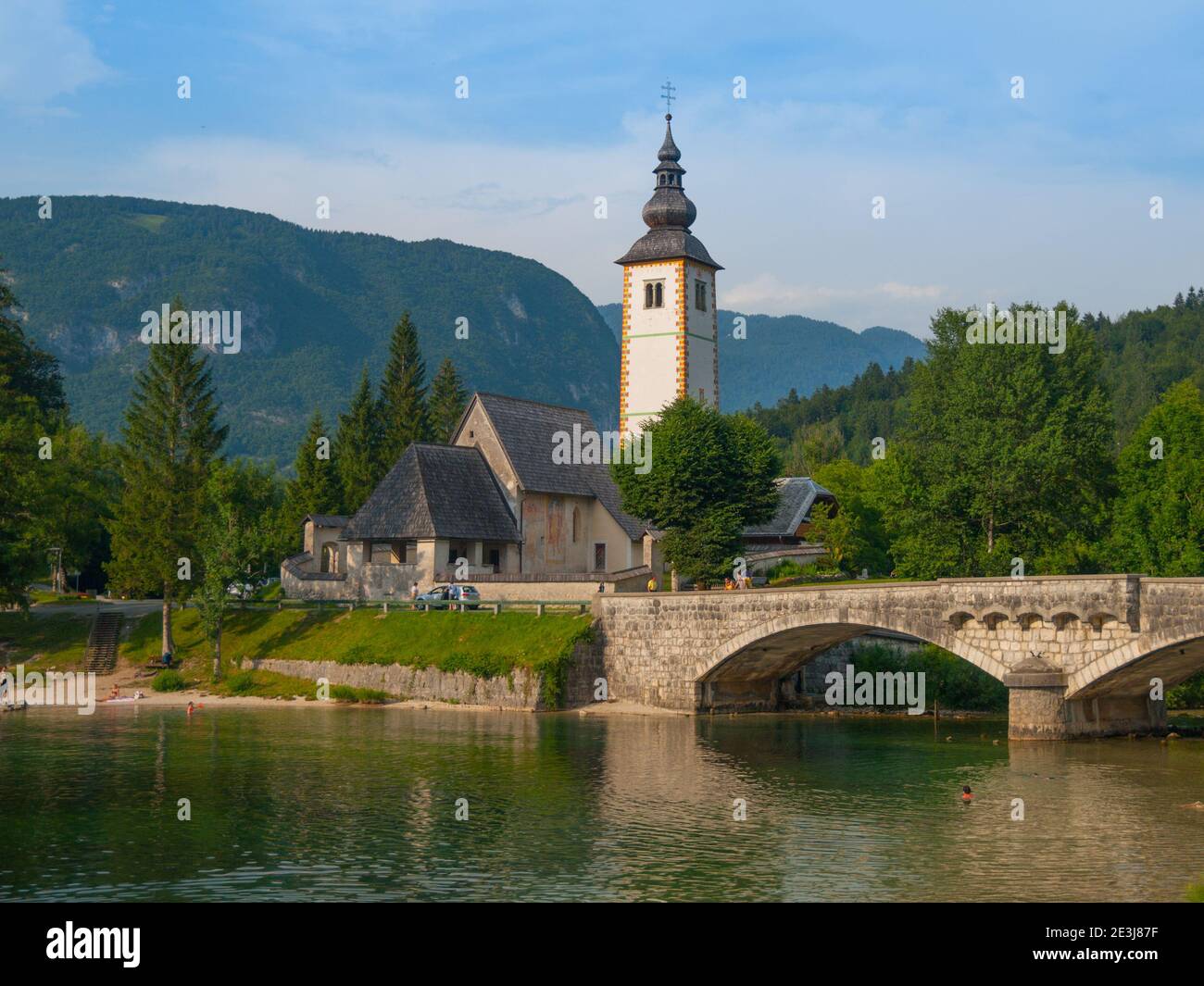 Church tower and stone bridge at Lake Bohinj in alpine village Ribicev Laz, Slovenia Stock Photo