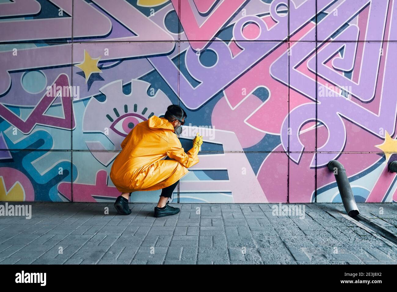 Street artist painting colorful graffiti on wall. Modern urban art ...
