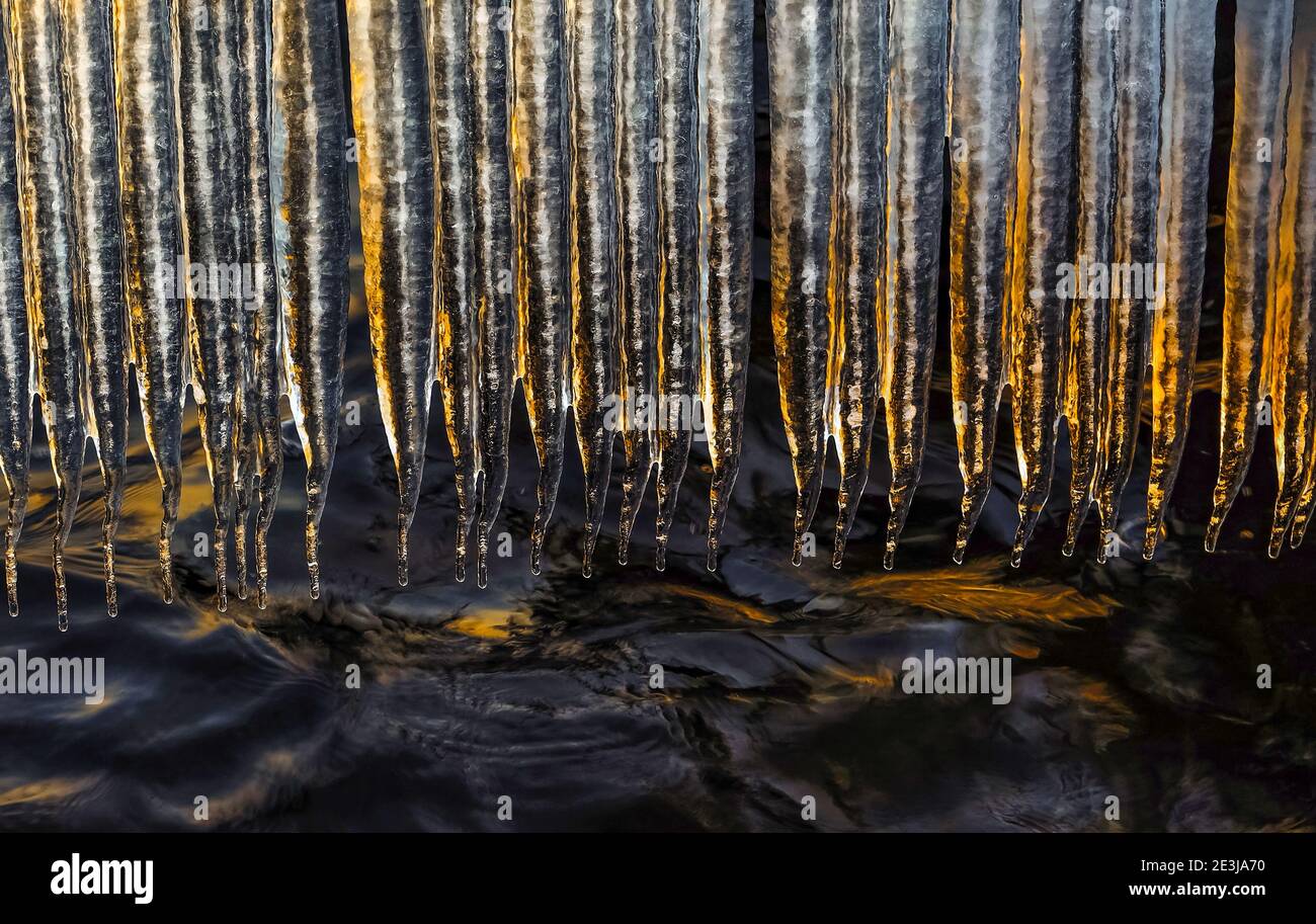 A row of icicles over the lake. They were lit by the evening sun and looked beautiful and romantic. Stock Photo