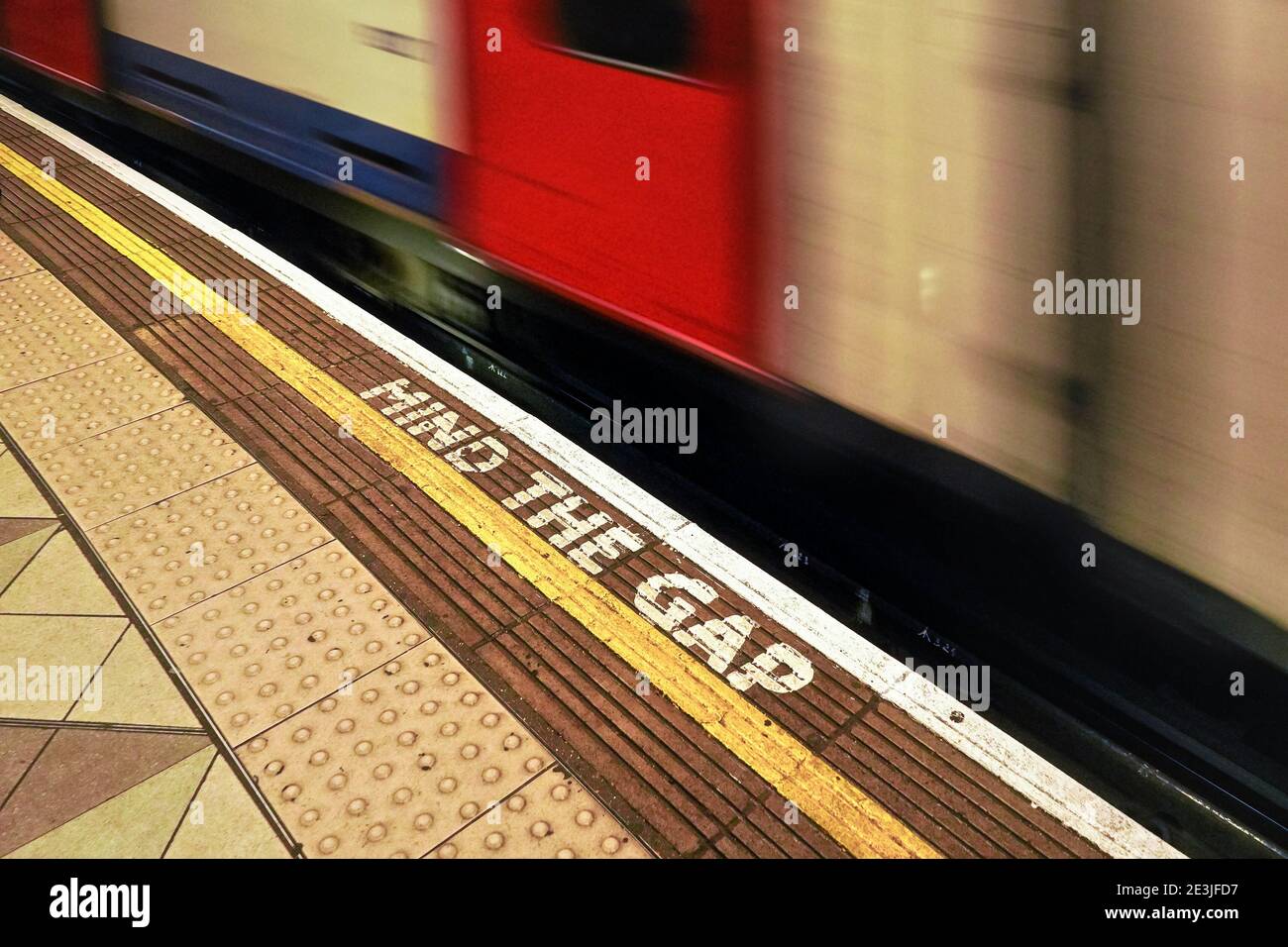London, United Kingdom - February 02, 2019: MIND THE GAP text on floor of London underground station, blurred train arriving behind white line Stock Photo