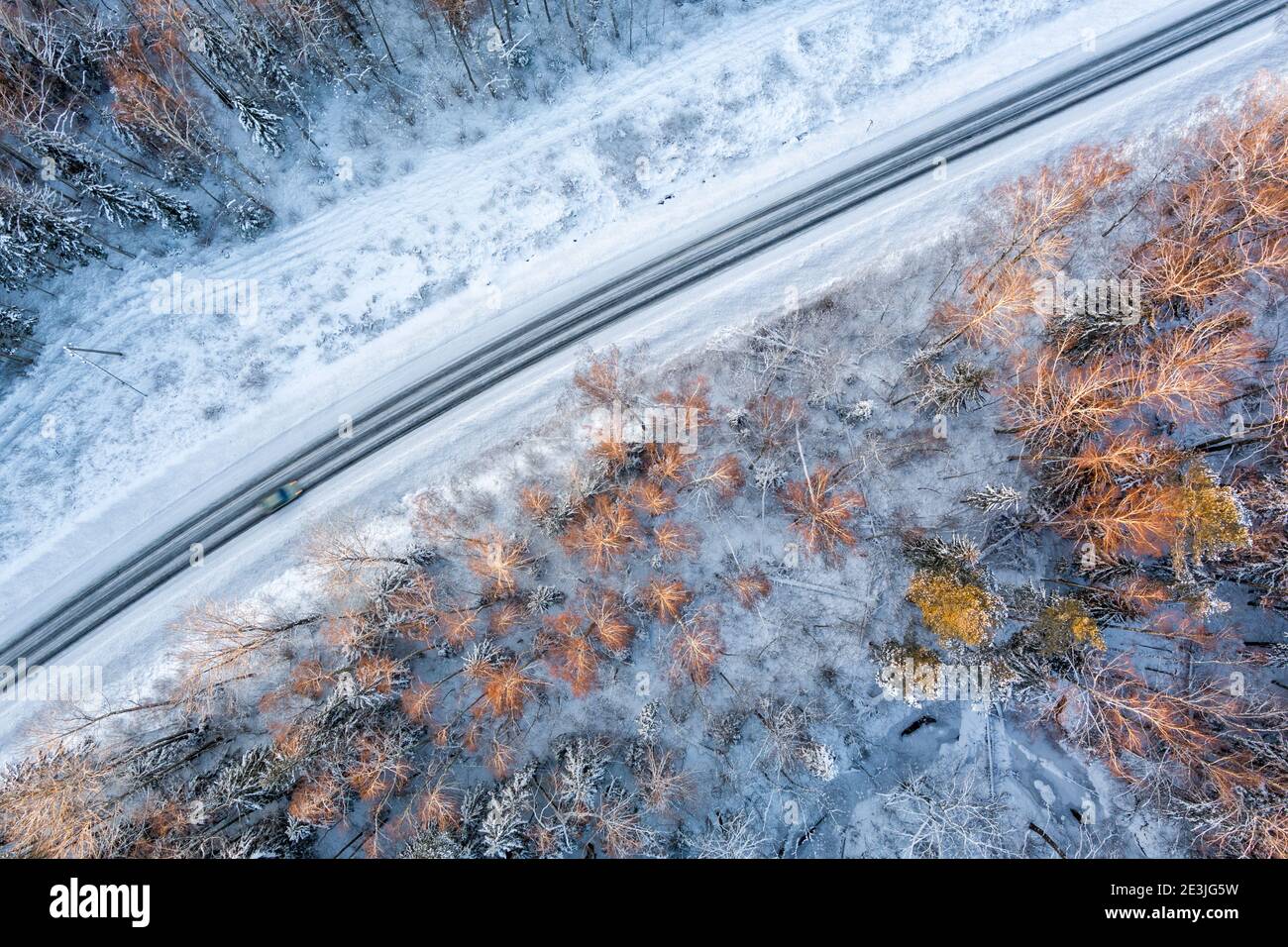 Aerial view from drone of car on curvy snow covered road in the winter forest Stock Photo
