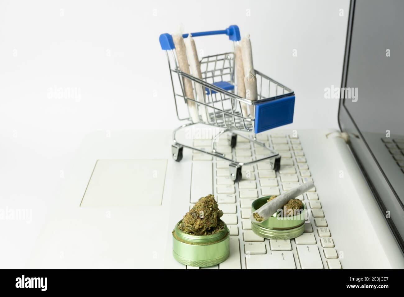 Marijuana buds on grinder with joints in shopping cart on laptop.Medical cannabis marijuana alternative medicine.Shopping online , weed store concept Stock Photo