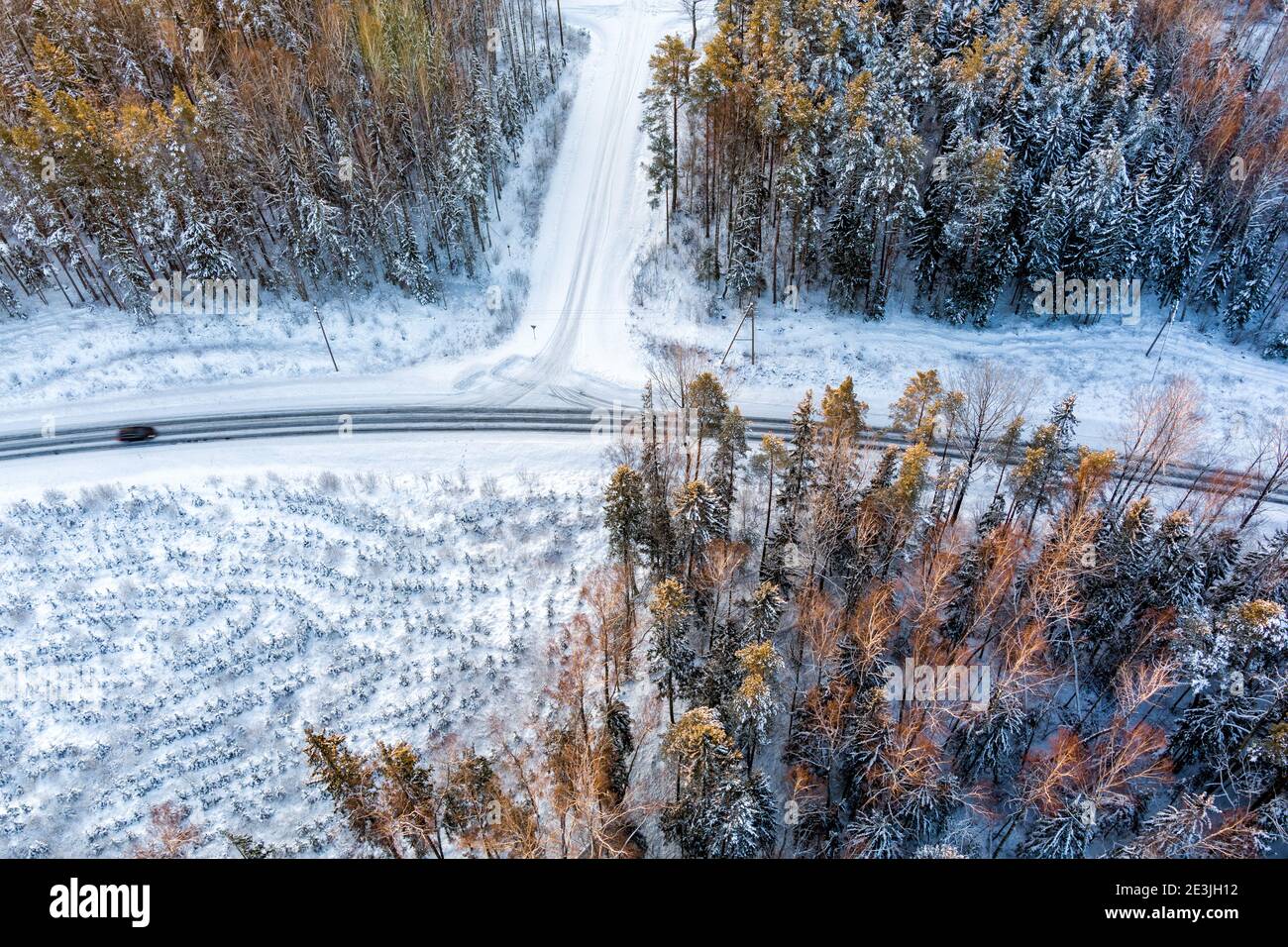 Aerial view from drone of car on curvy snow covered road in the winter forest Stock Photo