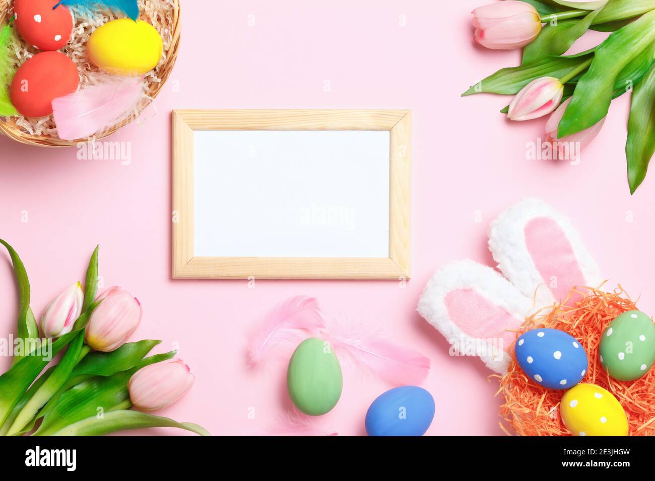 Easter eggs, bunny ears, tulips and frame with copy space on a pink ...
