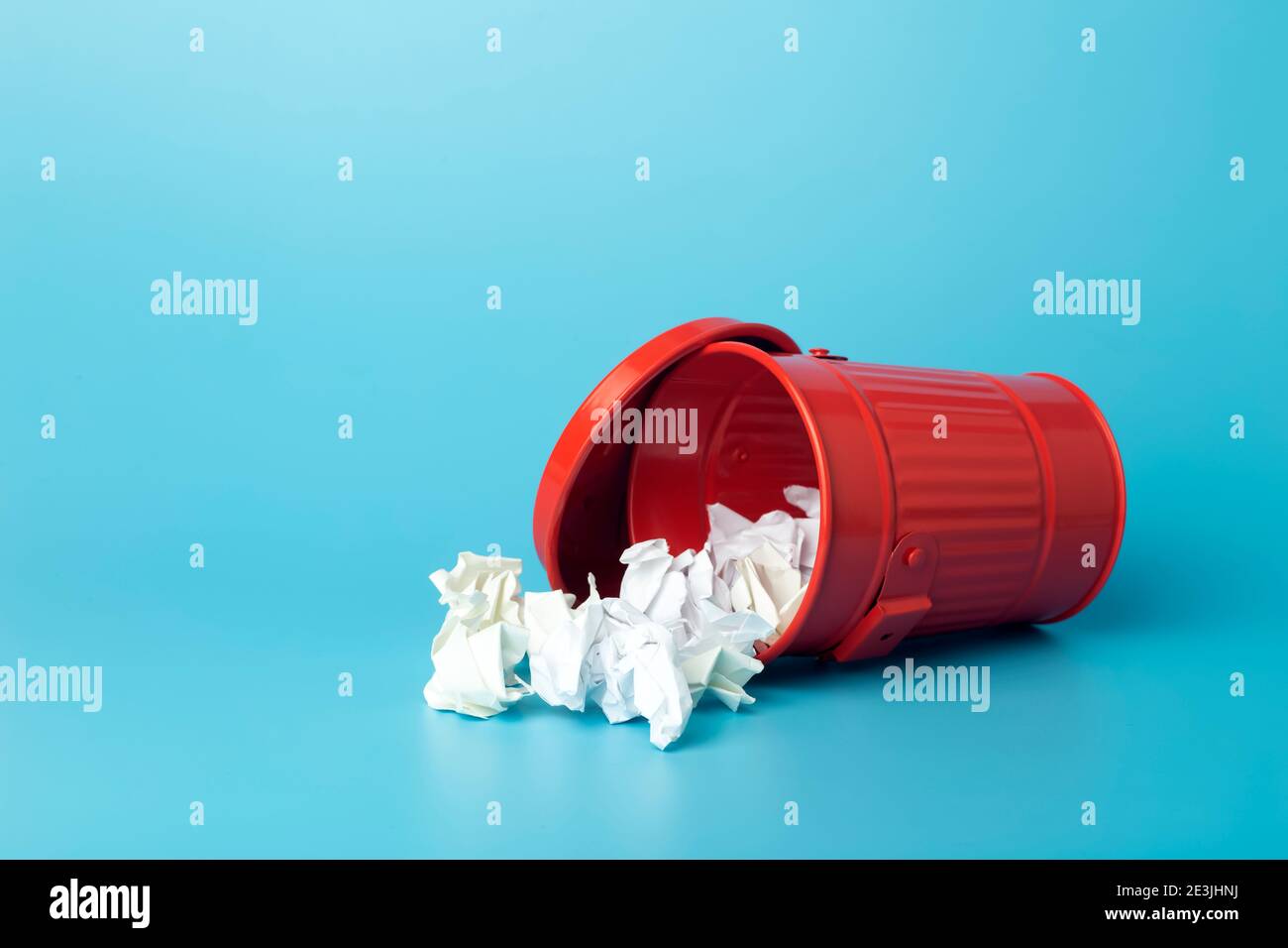 Paper trash and waste in a trash bin on a blue background. Waste and