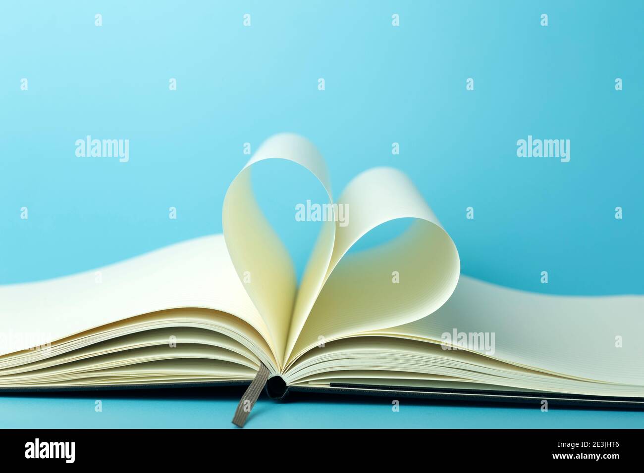 Heart made from white pages of notepad on a blue desktop background ...