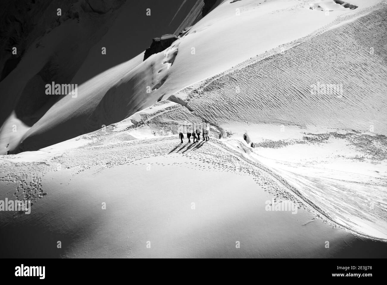 Man and majestic nature concept. Group of people hiking on snow covered mountain crest. Beautiful view from Agui du Midi in Mont Blanc massif in summe Stock Photo