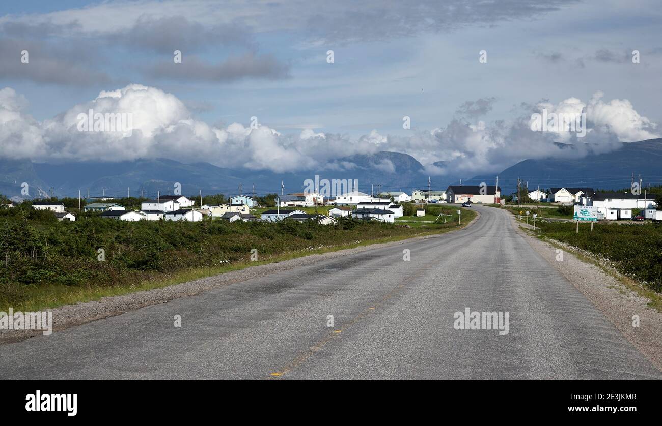 Small community in distance on road in coastal Newfoundland Stock Photo
