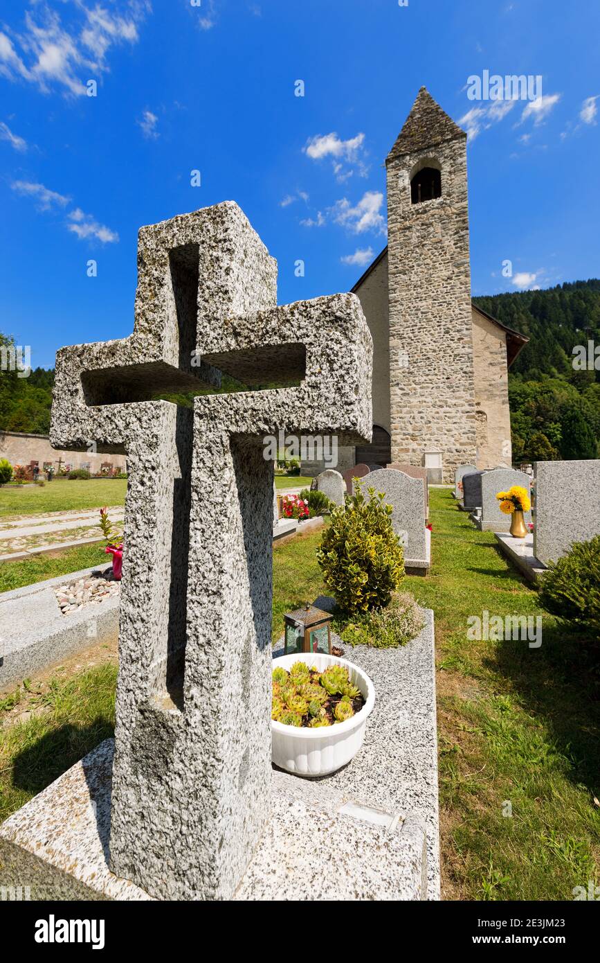 White granite cross in a cemetery with church. Pinzolo, Trento Italy Stock Photo