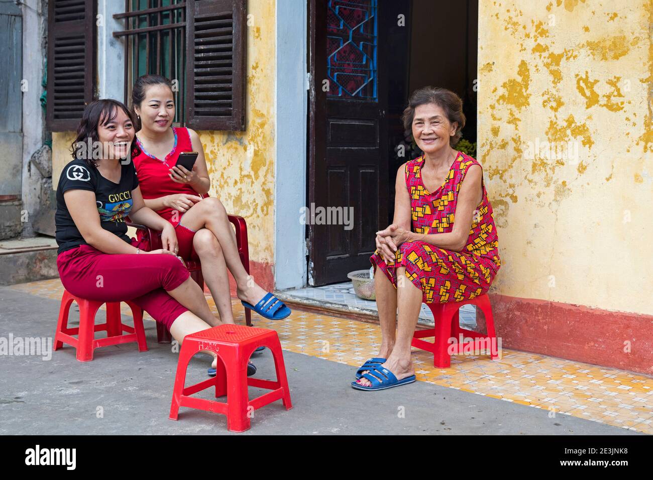 Vietnamese women sitting and chatting in front of their house in the city Ninh Binh in the Red River Delta of northern Vietnam Stock Photo
