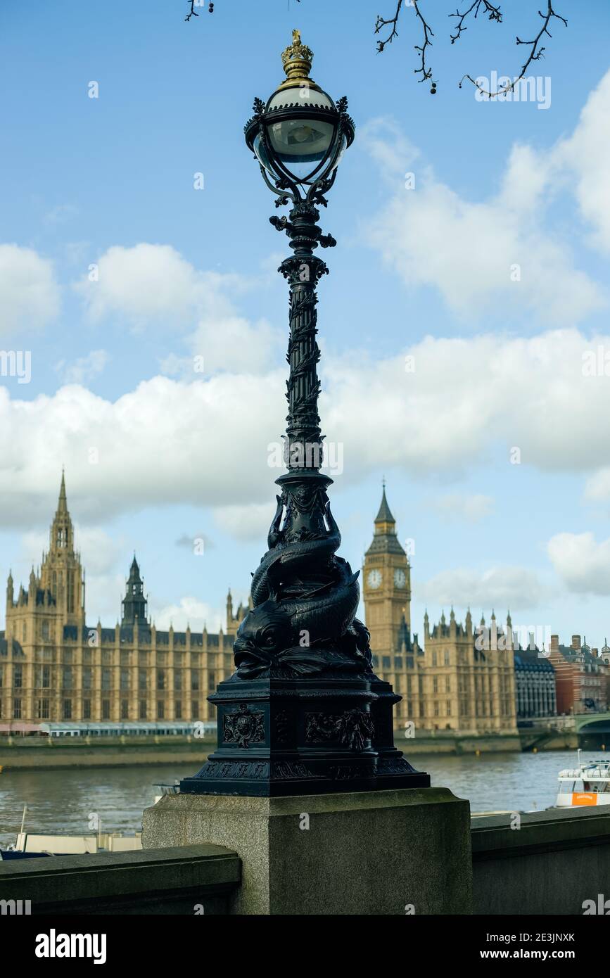 A 'Dolphin lamp standard' (±1860s) on the Embankment opposite the Palace of Westminster and Elizabeth Tower, Lambeth, London, UK Stock Photo