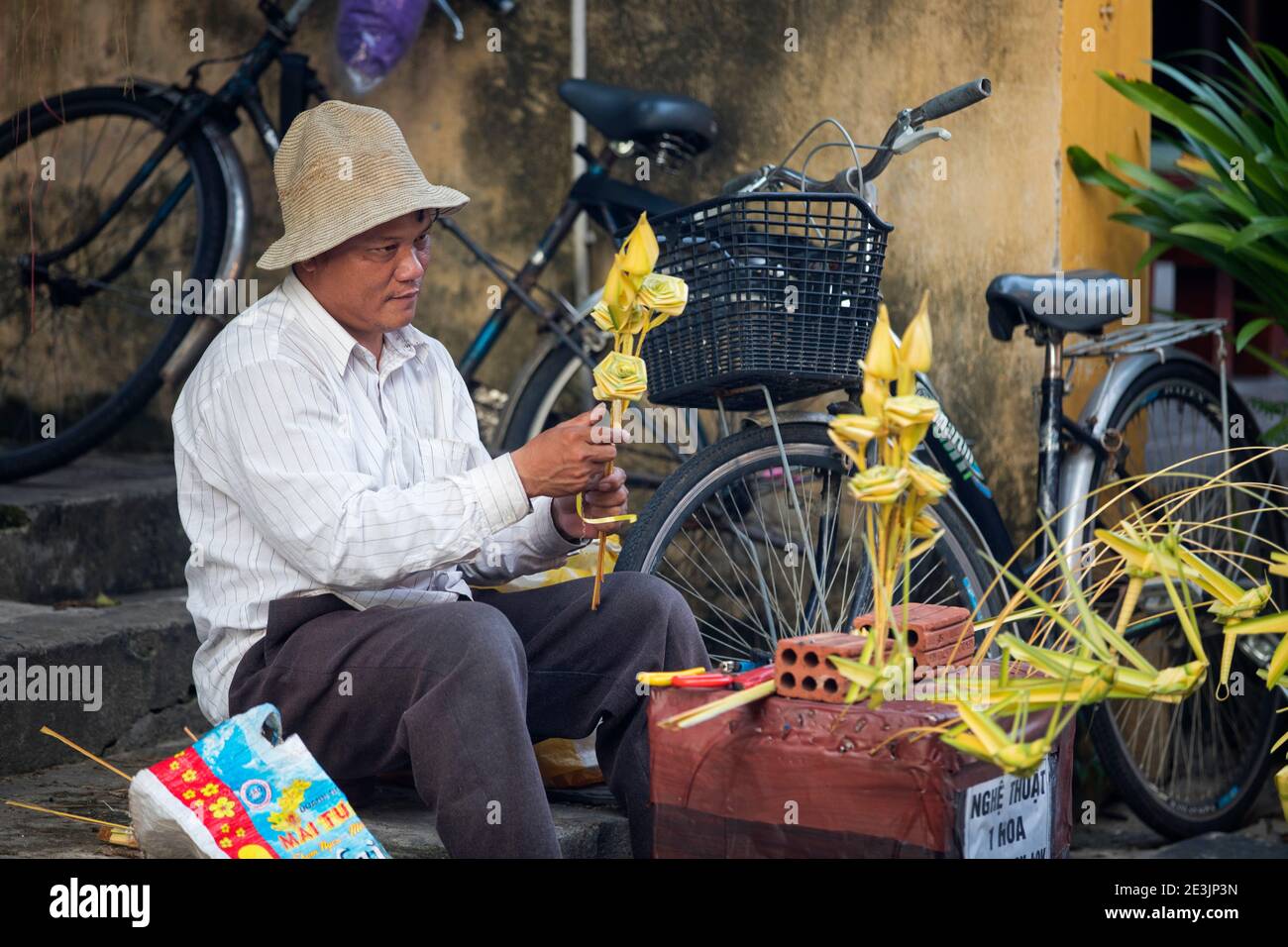 Vietnamese man making paper flowers on market in the city Hoi An / Fai-Fo / Faifoo, Quảng Nam Province, Central Vietnam Stock Photo