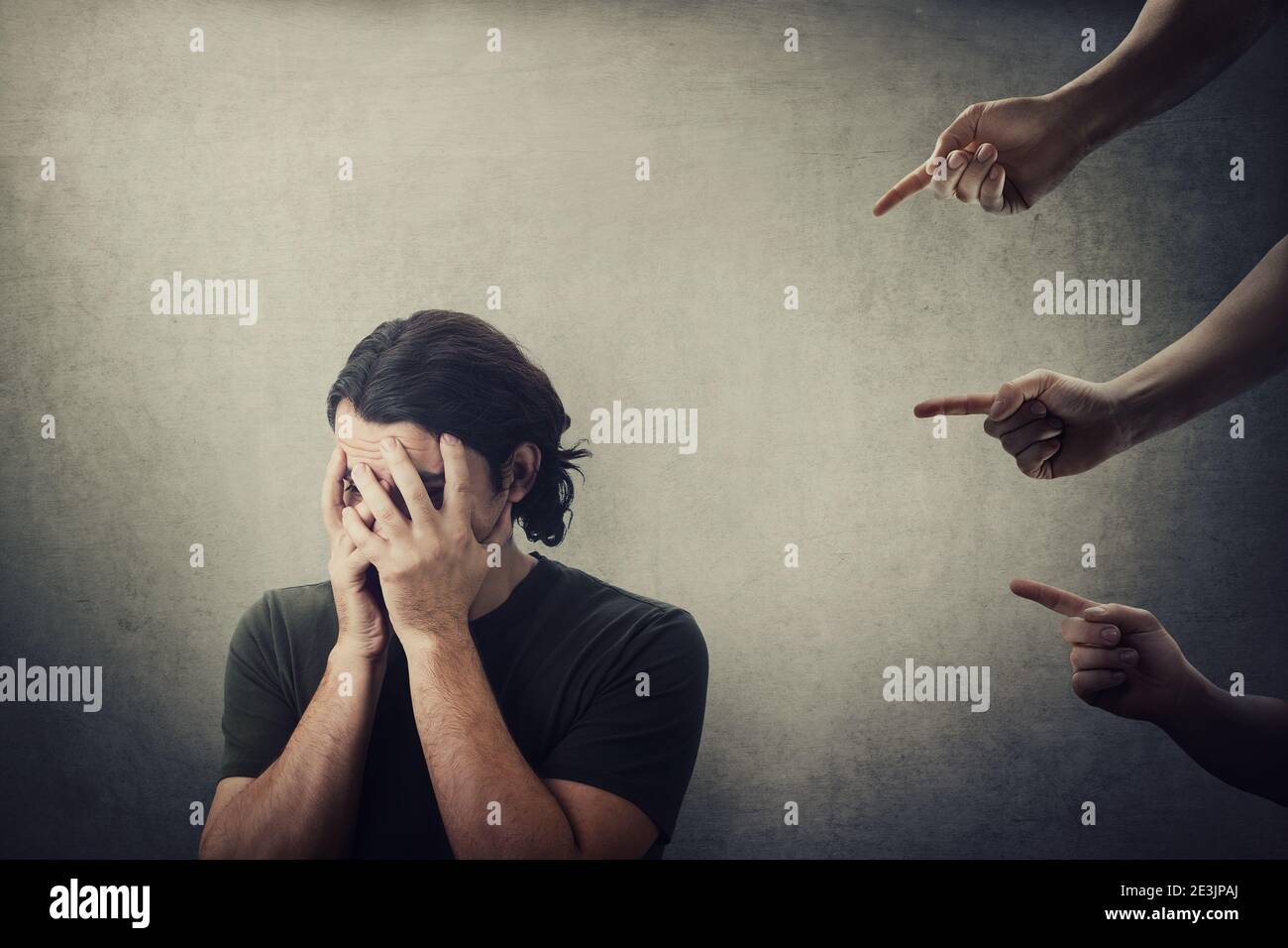 Disappointed and ashamed man, covers his face with palms, as many people fingers points to him from behind, blaming and scolding. Guy suffering emotio Stock Photo