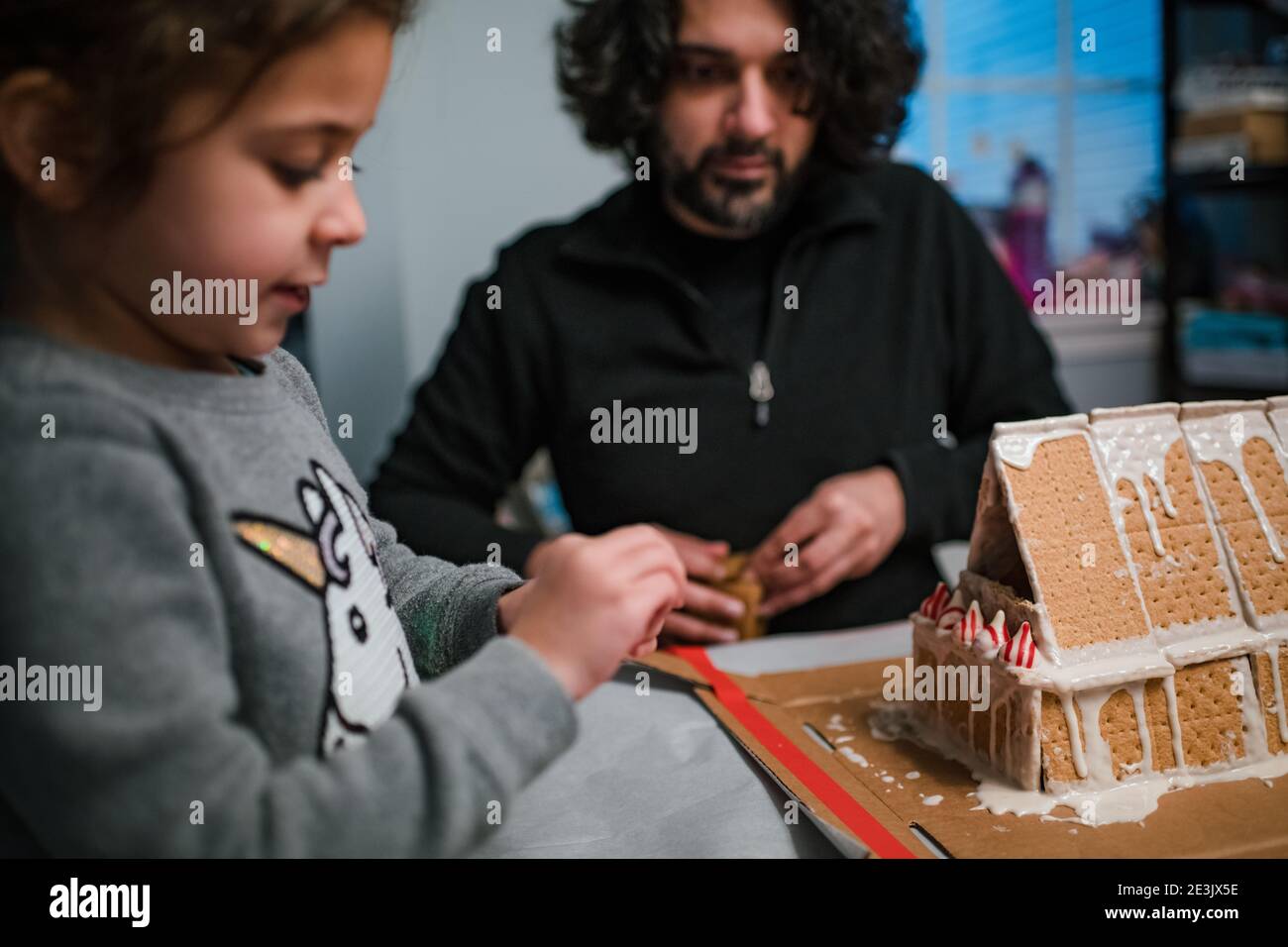 Dad and daughter building gingerbread house together Stock Photo