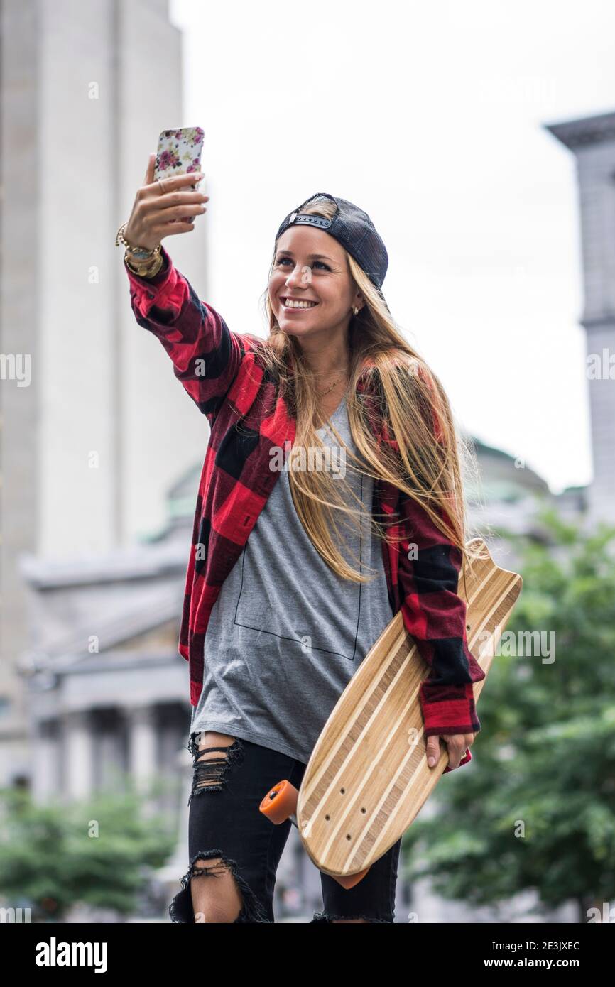 Stylish female urbanite with skateboard taking a selfie downtown, Montreal,  Quebec, Canada Stock Photo - Alamy