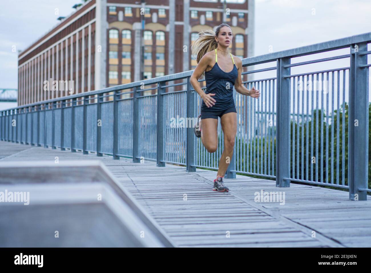 Female athlete running on urban boardwalk, Montreal, Quebec, Canada Stock Photo