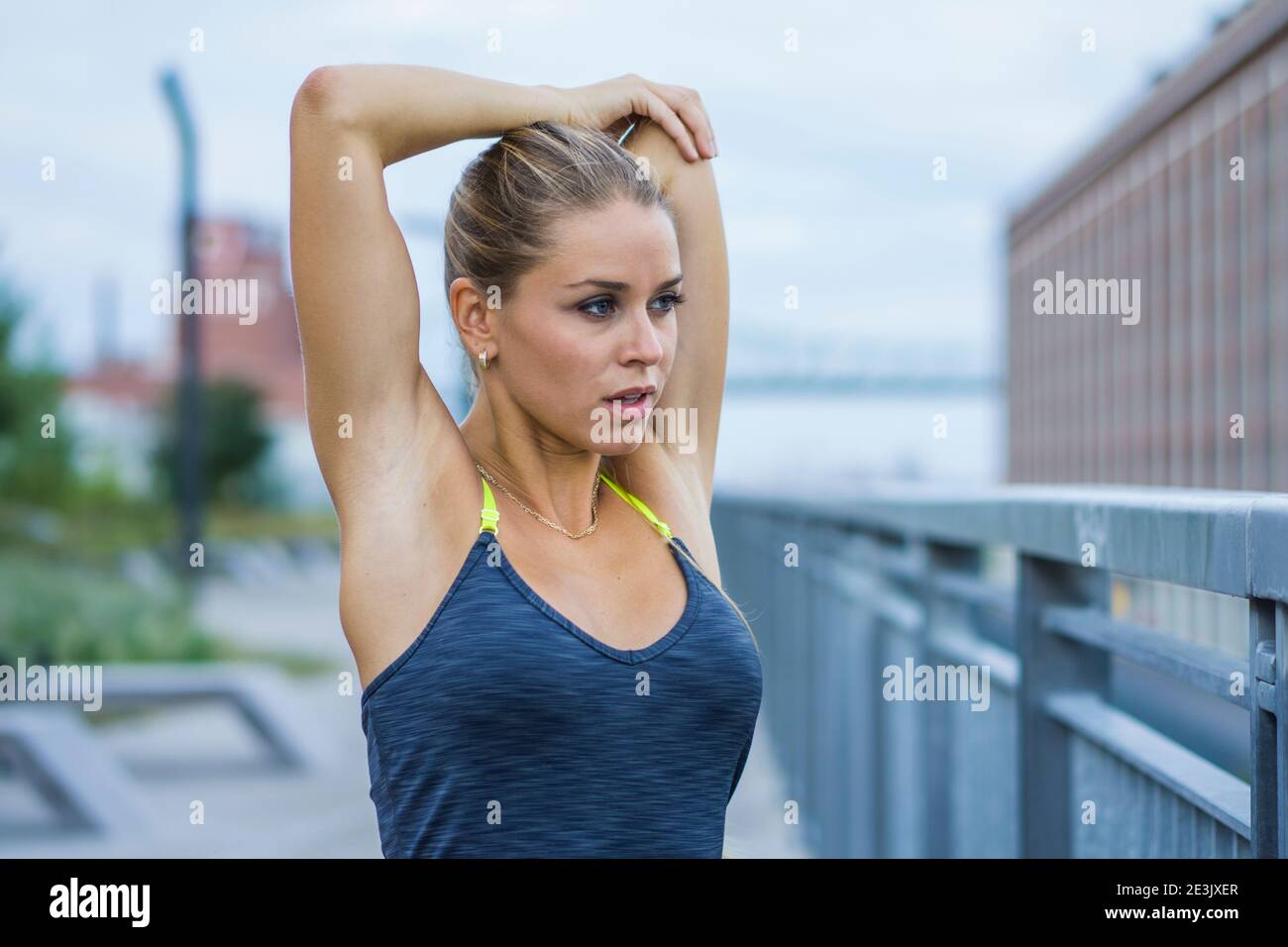 Blonde female athlete stretching on urban boardwalk, Montreal, Quebec, Canada Stock Photo