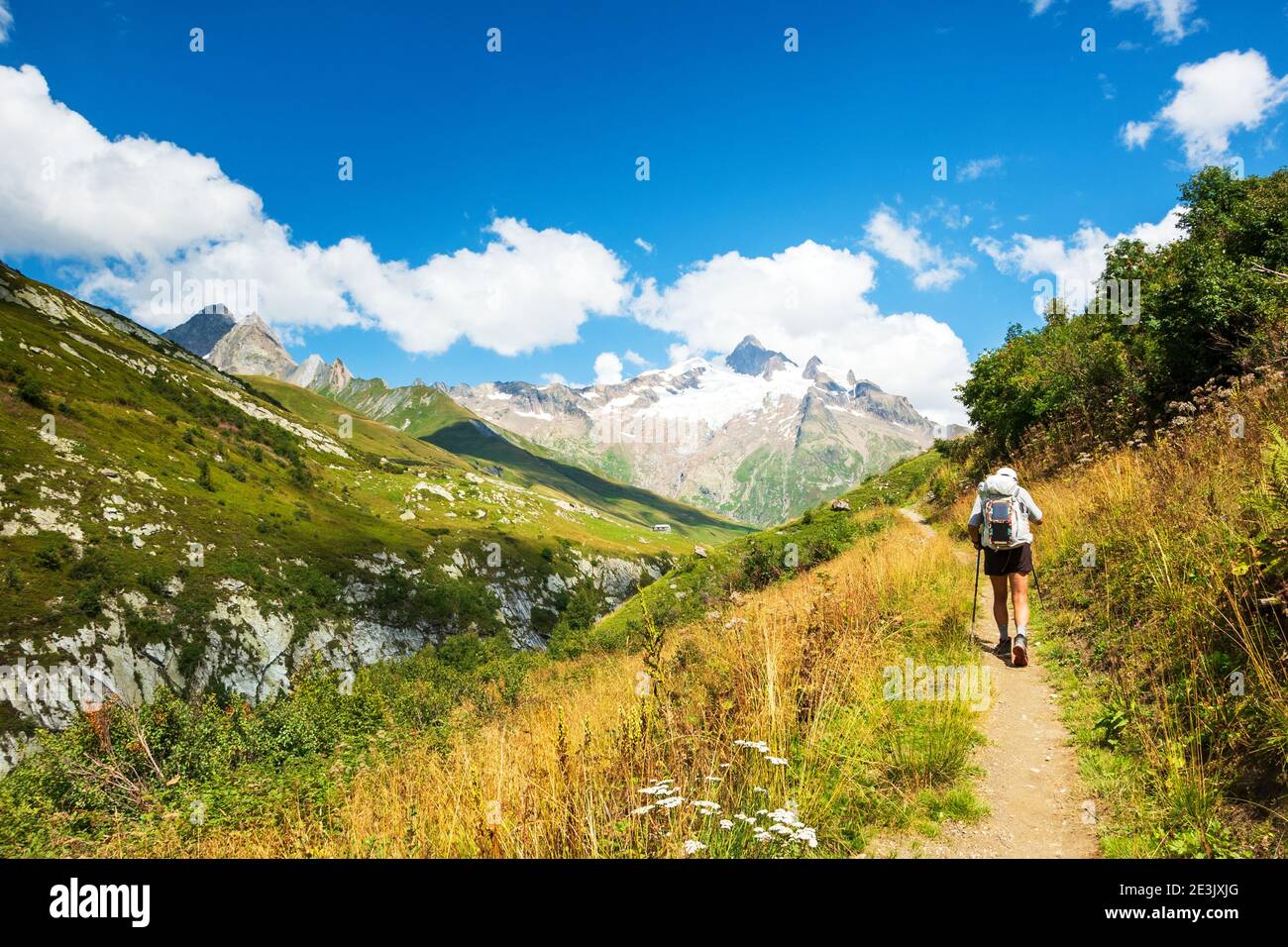 Senior man hiking French Alps in summer with solar backpack. The
