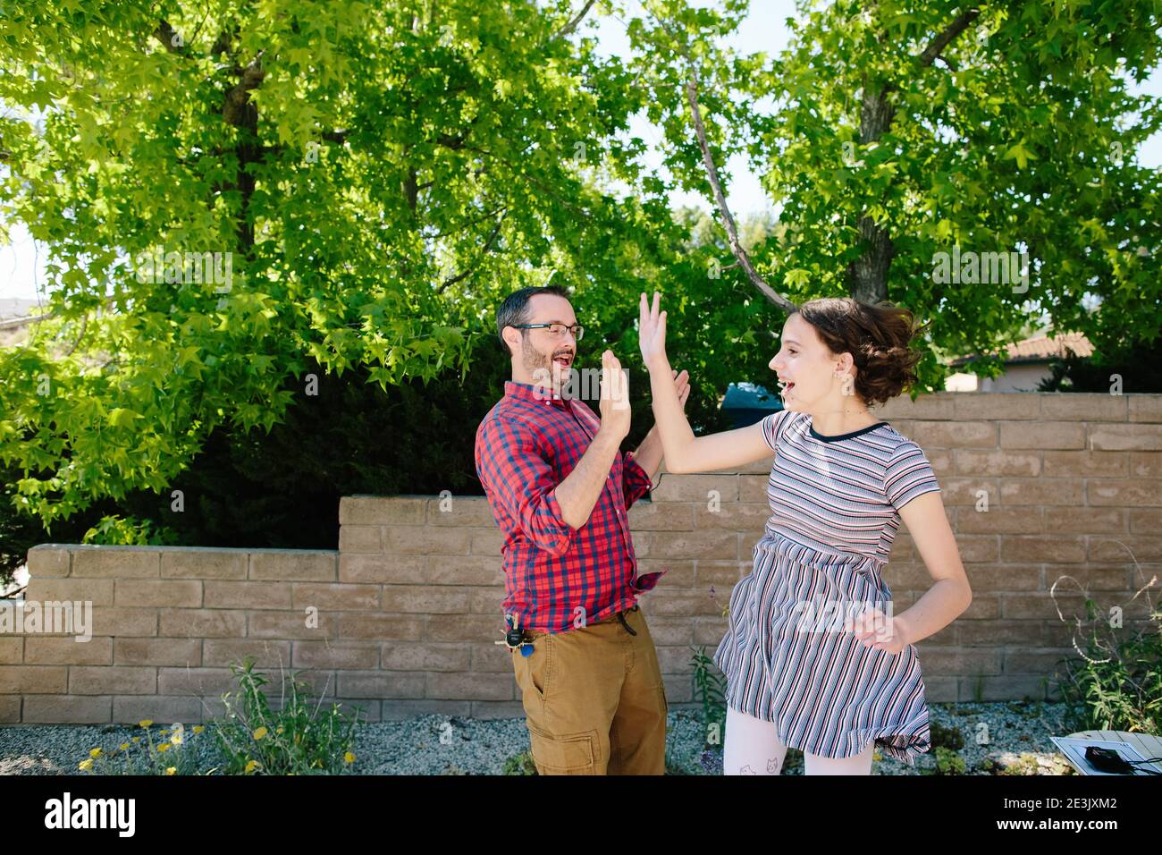 Teen Girl Jumps To Give Her Dad A High Five Stock Photo