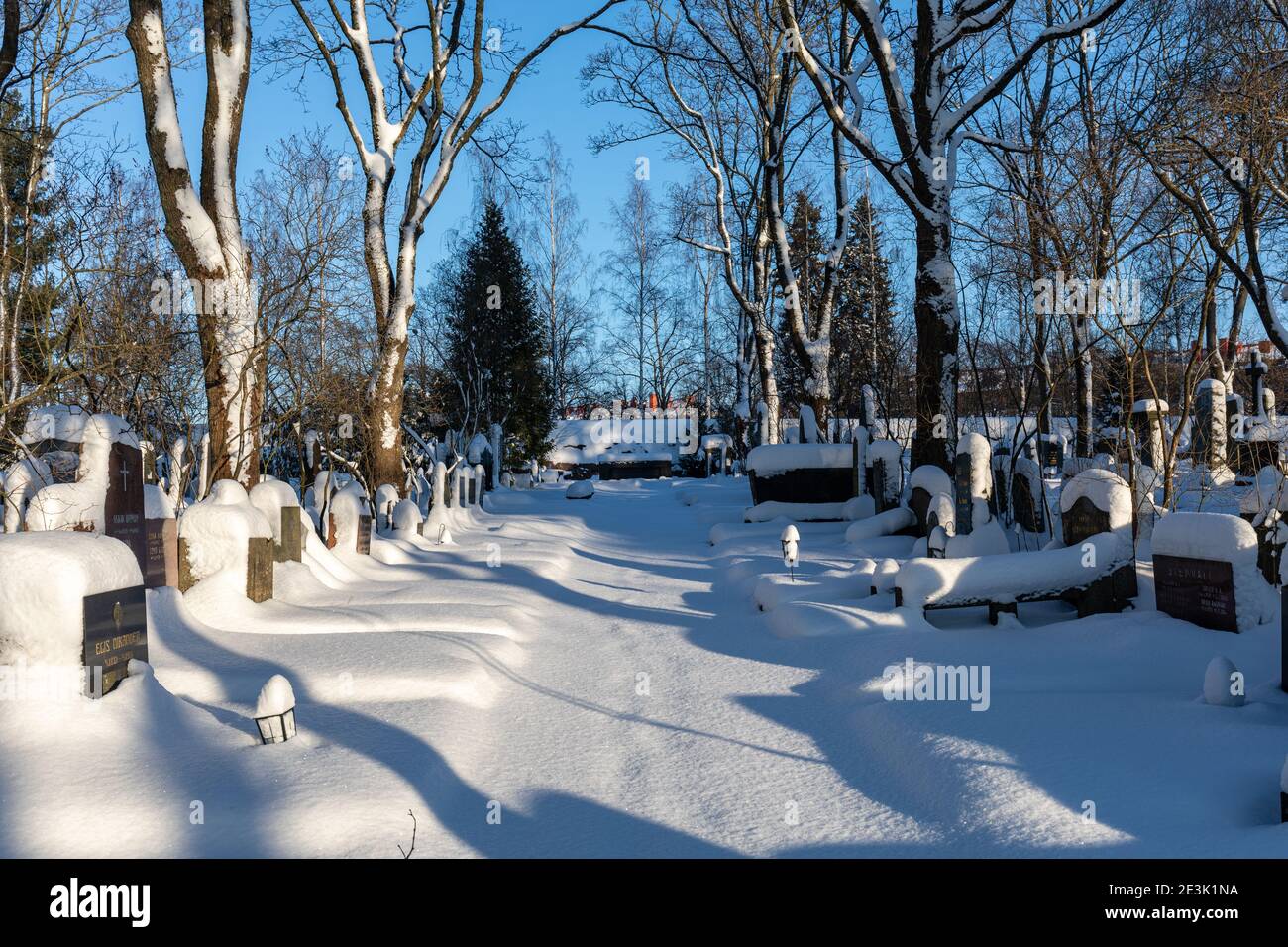 Snow covered graves and headstones at Hietaniemi cemetery on a sunny winter day in Helsinki, Finland Stock Photo