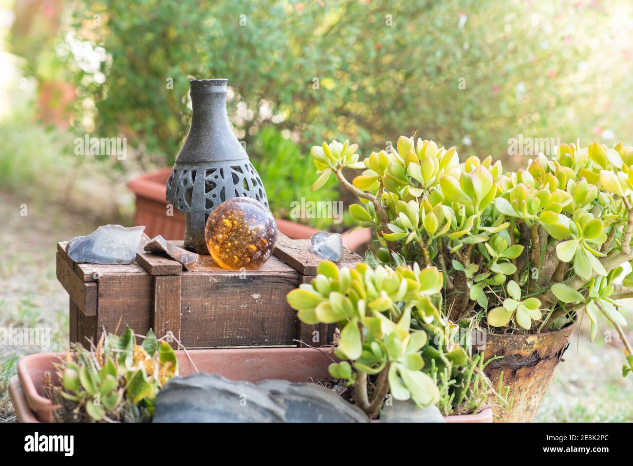 Recycled garden design and low-waste lifestyle. Rustic wooden box with vase and magic glass ball in a garden. Stock Photo