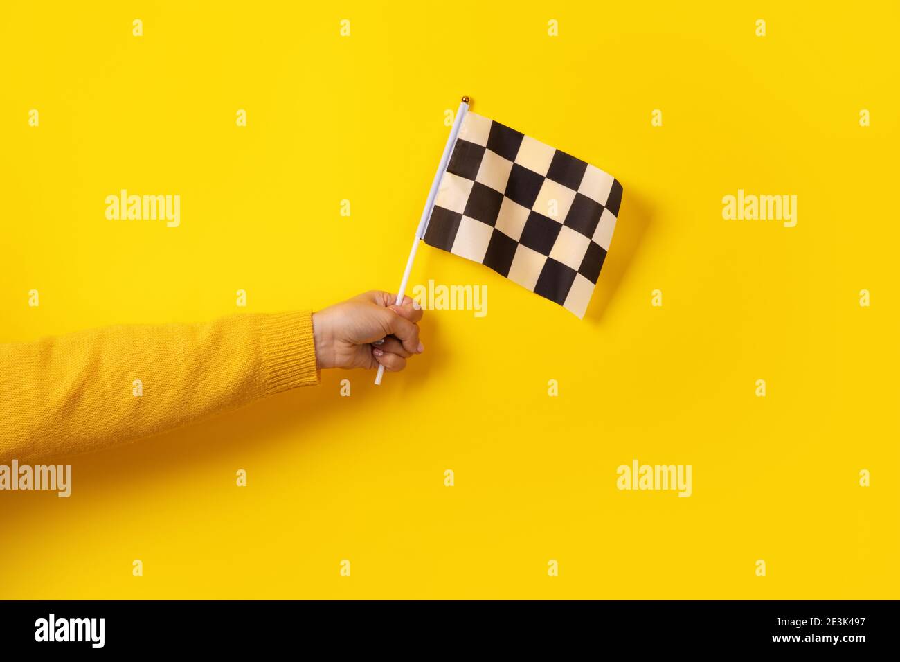 checkered flag in hand over yellow background Stock Photo