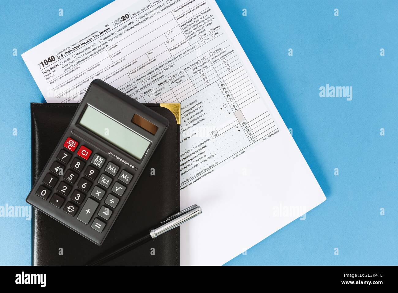 Tax Form 1040 and Calculator on Light Blue Background Stock Photo