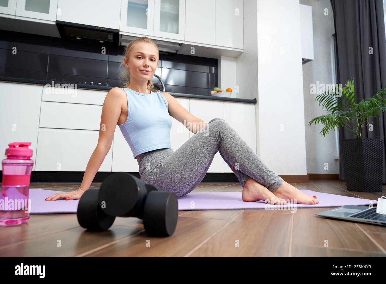 Happy active woman in sport clothes training on yoga mat at home. Pleasant  blonde using modern laptop for online course during workout Stock Photo -  Alamy
