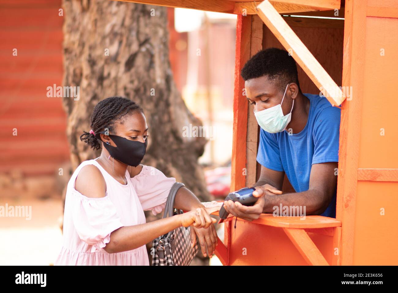 nigerian woman at a pos service kiosk to withdraw cash entering her details into the pos machine Stock Photo