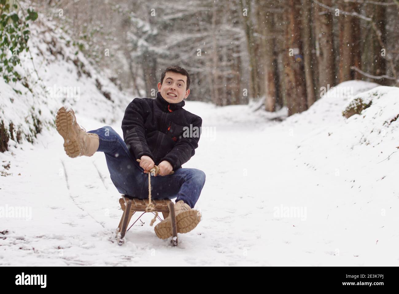 It's getting to fast - Man riding a sleigh with frightened face, struggling and falling off the sledge Stock Photo