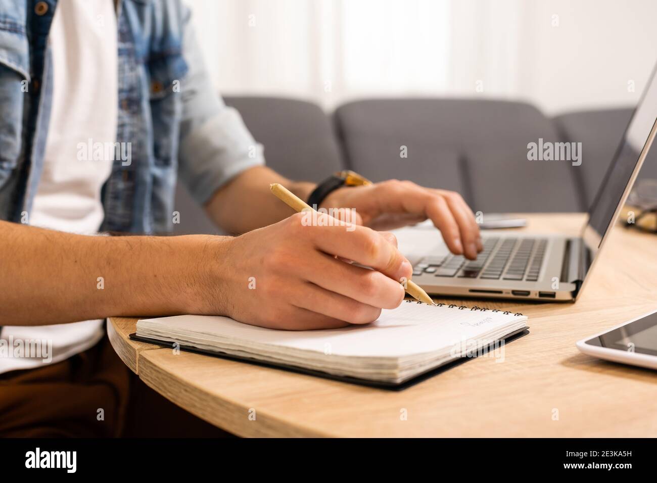 Portrait Of A Man Working At Home On Some Project He Is Sitting At A Table Drawing Ideas On A Notebook With His Laptop In Front Of Him Stock Photo Alamy